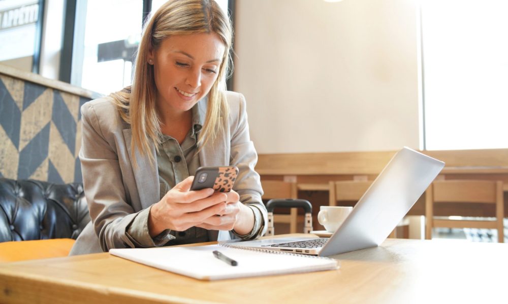 Frau prüft ihre Zeiterfassung-Software auf dem Smartphone Frau prüft ihre Zeiterfassung-Software auf dem Smartphone