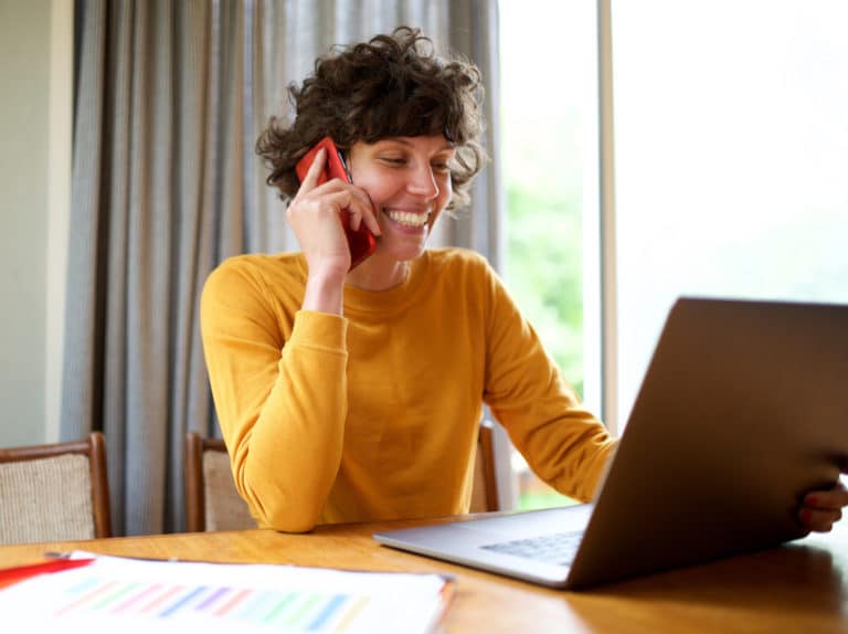 Frau telefoniert und schaut sich Zeitwirtschaft Tool auf dem Laptop an